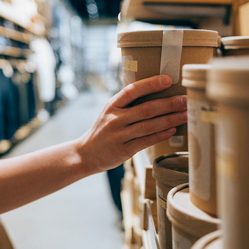 Kvinde vælger produkt i brunt genbrugspap fra butikshylde